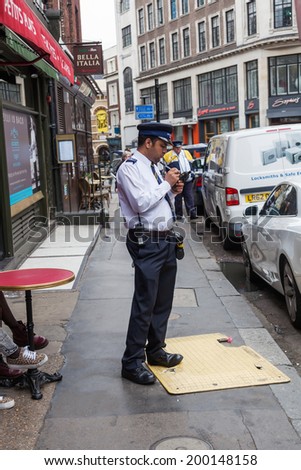 LONDON - MAY 21: street scene in London with unidentified people and a civil encounter officer who writes a ticket on May 21, 2014 in London. London is the most populous city in Europe.
