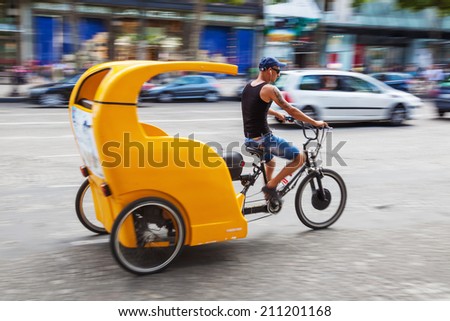 PARIS - AUGUST 03: cycle rickshaw in motion blur on the Champs Elysees with unidentified people on August 03, 2014 in Paris. They are widely used in major cities wroldwide, hired by passengers.