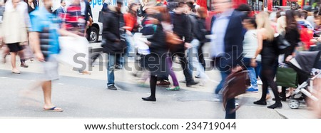 busy crowd of people in motion blur crossing a city street