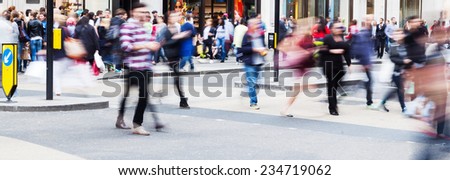 busy crowd of people in motion blur crossing a city street