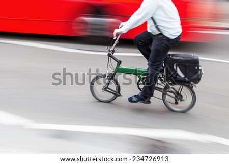 business man with a folding bike in the city traffic in motion blur