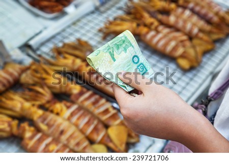 hand reaching Thai money at a food stall in Bangkok