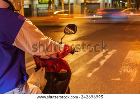 night picture with small depth of field of a scooter rider waiting at the traffic lights