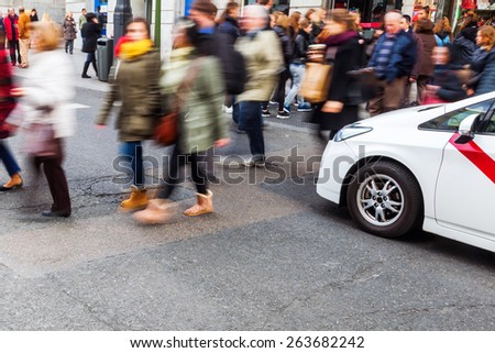 crowd of people in motion blur crossing a city street