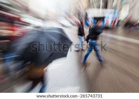 picture with zoom effect of people crossing a rainy street