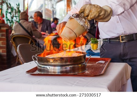 cook burns a traditional kebab dish in an earthenware vessel on the restaurant table in Istanbul, Turkey
