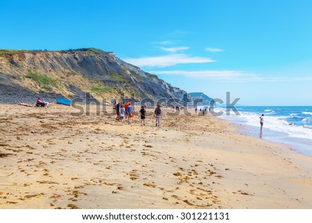 CHARMOUTH, ENGLAND - JULY 05, 2015. beach at Charmouth, Dorset, England, with unidentified people. The cliffs above the beach are a noted source of fossils from the Jurassic period.