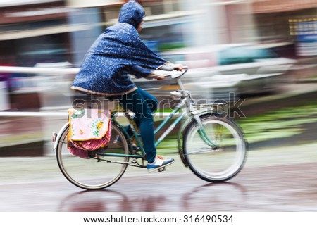 cyclist on the move in the rainy city in motion blur