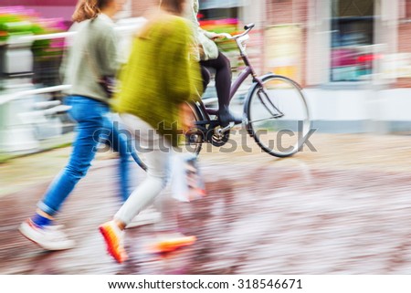 pedestrian and bicycle rider in motion blur on a rainy day in the city