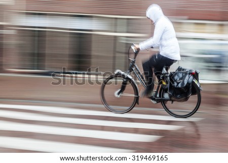 cyclist on the move in the rainy city in motion blur