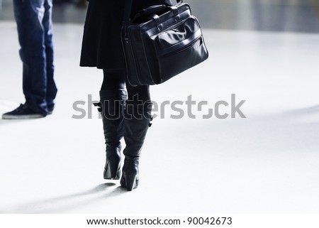 woman with a bag walking in a station