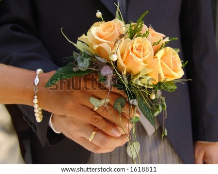 Just married. Bride and groom with wedding bands, holding the bouquet.