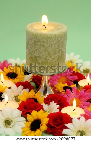 Romantic green candle and flowers on green