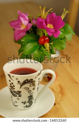Rosehip tea cup and roses on the table