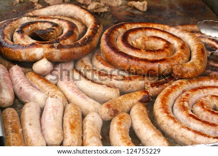 Photograph of fresh Italian sausage being grilled outdoors for carnival food menu, also known as fair food or street food.