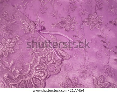 Detail of a lavender Oriental blouse sleeve with floral lace overlay with shiny threads woven through it.