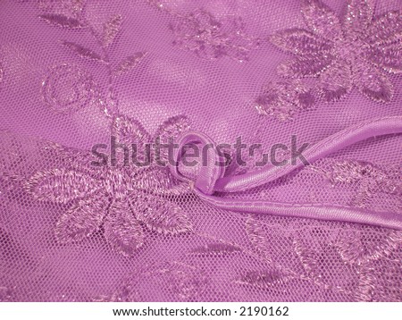 Detail of a lavender Oriental blouse sleeve with floral lace overlay with shiney threads woven through it.