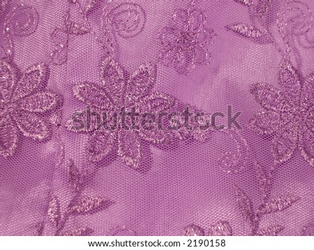 Detail of a lavender Oriental blouse sleeve with floral lace overlay with shiney threads woven through it.