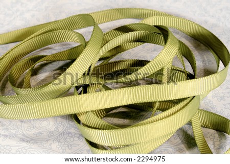 Green grosgrain ribbon coiled and arranged on a blue and white background.