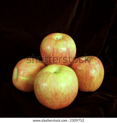 Red apples stacked on a black surface with a black background.
