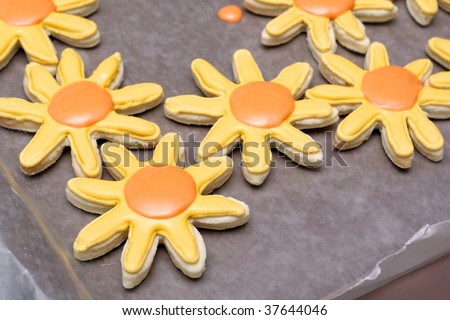 Homemade sugar cookies, decorated with royal icing.  Flower shaped cookies on a wax paper covered cookie sheet.