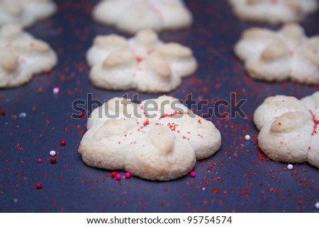 Sprtiz cookies with red sugar on a cookie sheet.
