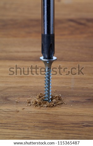 A screwdriver driving a screw into a wood surface