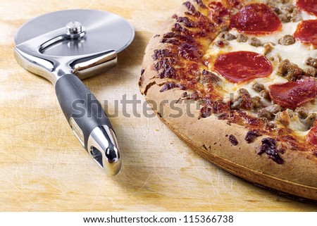 Pizza cutter and pizza on a brown background