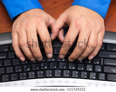 Close-up cropped shot of a human hands typing on black keyboard.