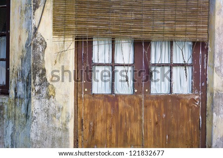 A closed door with a thatched sun blocker in front of it in Kochi, India.