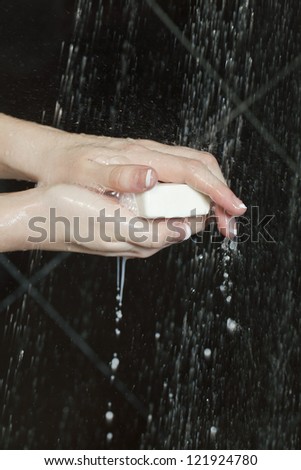 Human hand washing with bar of soap under the running water