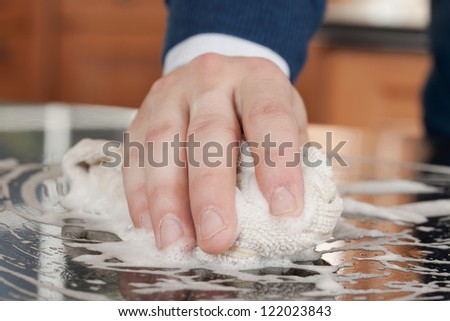 Human hand wiping a table with a soapy rag