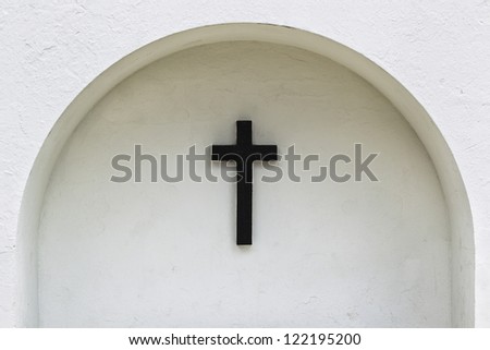 View of a cross sign on arched white wall.