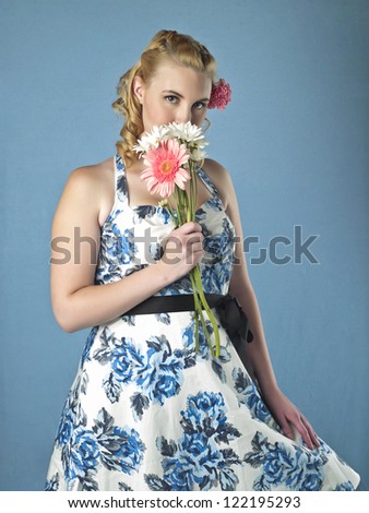 An attractive woman while smelling a flower looking at the camera