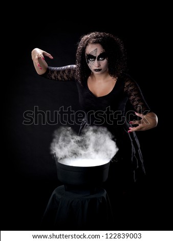 Witch stands beside cauldron