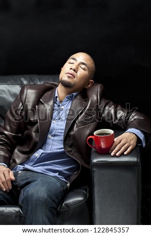 Young African American businessman relaxing on a couch with a cup of coffee,