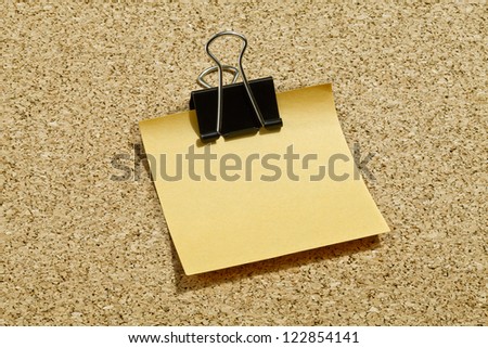 Close up image of yellow post it paper with black metal paper clip