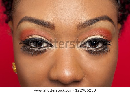 Extreme close-up of a African American models eyes against red background