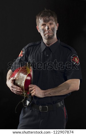 Portrait of a dirty fireman holding his helmet at his side