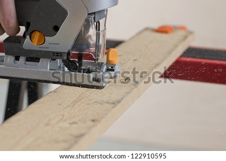 Closed up shot of a craftsman\'s hand using a jigsaw to cut a piece of wood