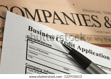 Detail shot of a business credit application with a pen and news paper.