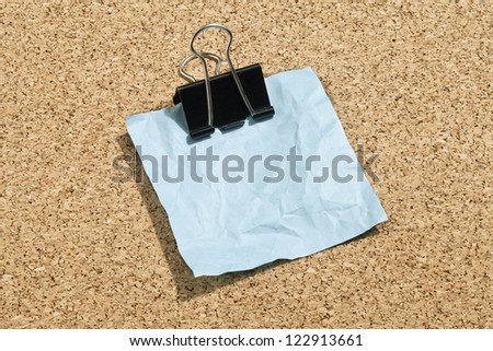 Close-up image of a crumpled blue paper with metallic clip