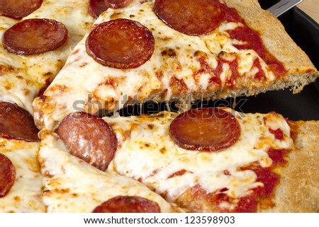 Horizontal cropped image of slices of pepperoni pizza on a black pan