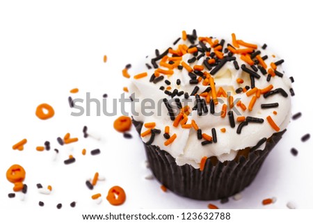 Cupcake with white icing decorated with sprinkles on white background.