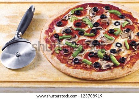 Image of thin crust pizza with a slicer on a wooden table