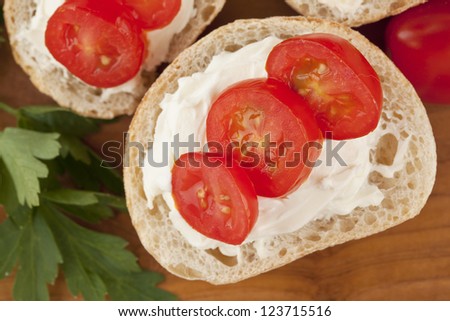 Close-up image of a slice of bread with slice tomatoes and butter on the wooden table
