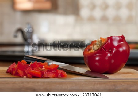 Sliced red bell pepper and knife over a blurred  kitchen background