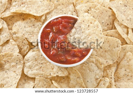 Close up image of nachos with bowl of salsa dip
