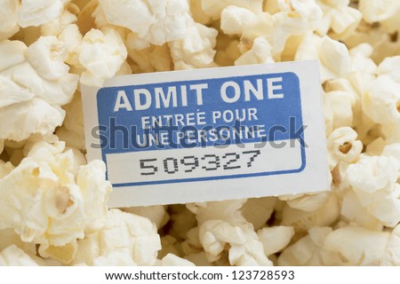 Movie ticket with salted popcorn in a background \