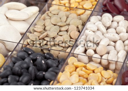 Close-up cropped shot of variety of pulses in glass container with partition.